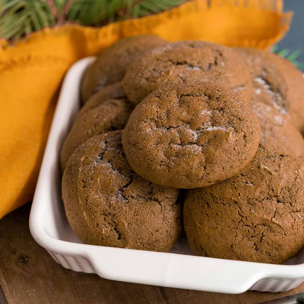 White bowl with finished molasses cookies stacked in it.