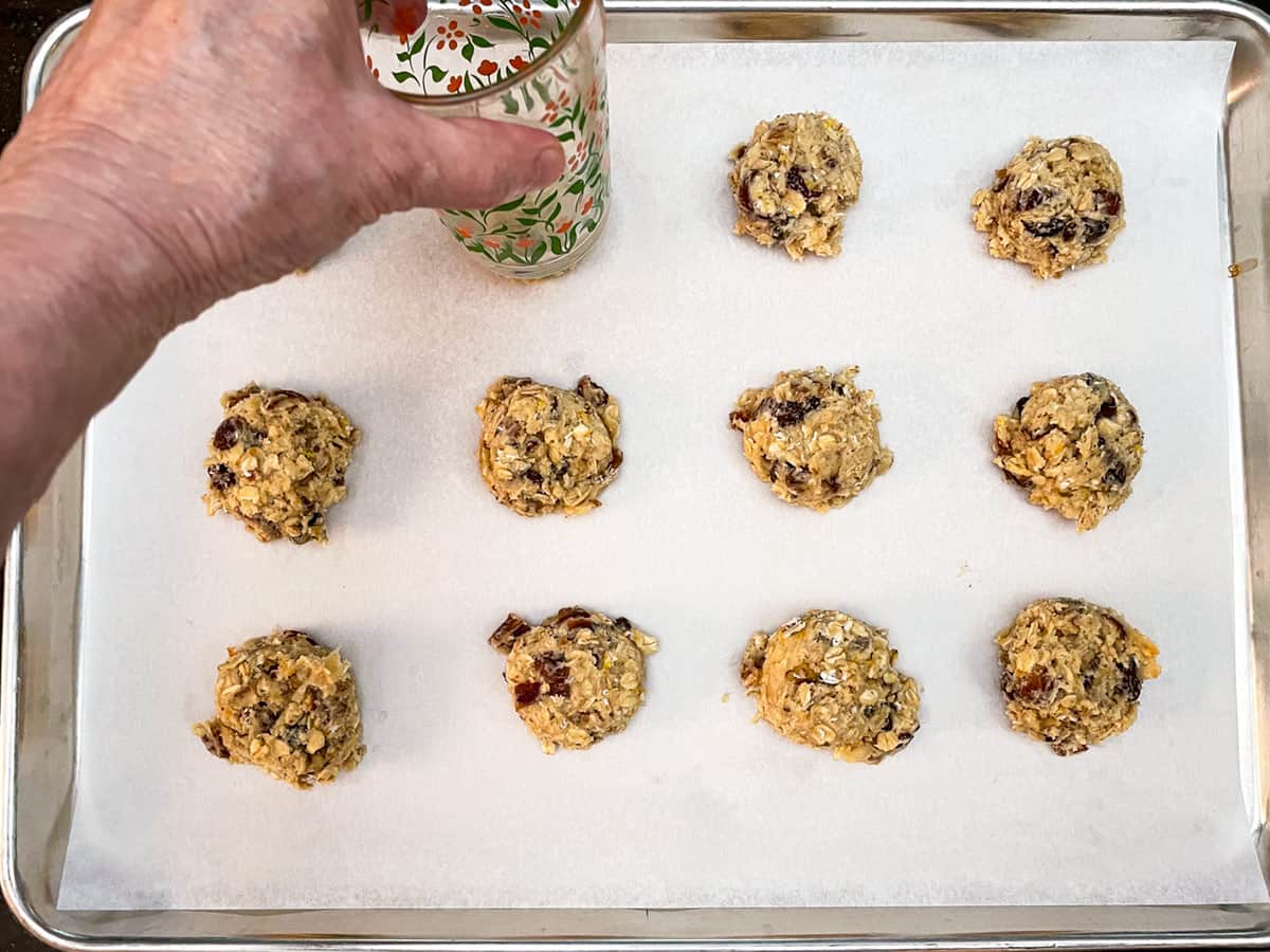 Pressing down cookie mounds to flatten the tops a little with the bottom of a water glass.
