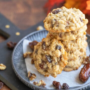 Soft Oatmeal with dates and walnut cookies on a metal pewter plate with walnuts, whole dates and raisins.