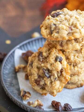 Soft Oatmeal with dates and walnut cookies on a metal pewter plate with walnuts, whole dates and raisins.