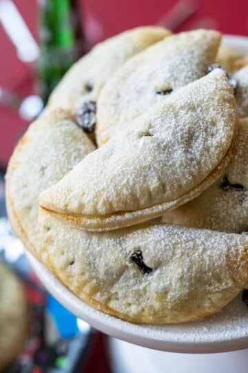 Rum Raisin with Orange filled Cookies on a with dish and sprinkled with powdered sugar.