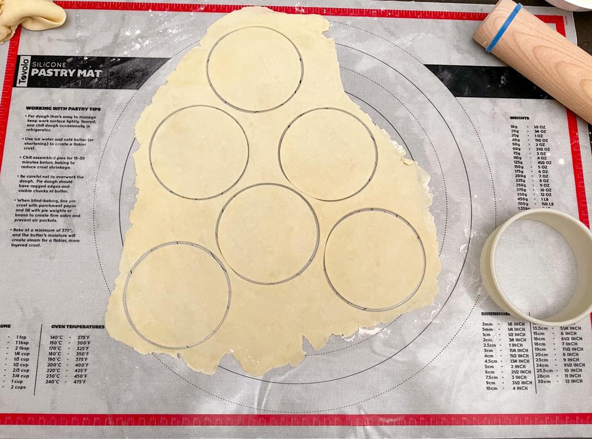 6 4-inch cookie dough circles cut out on pastry sheet.