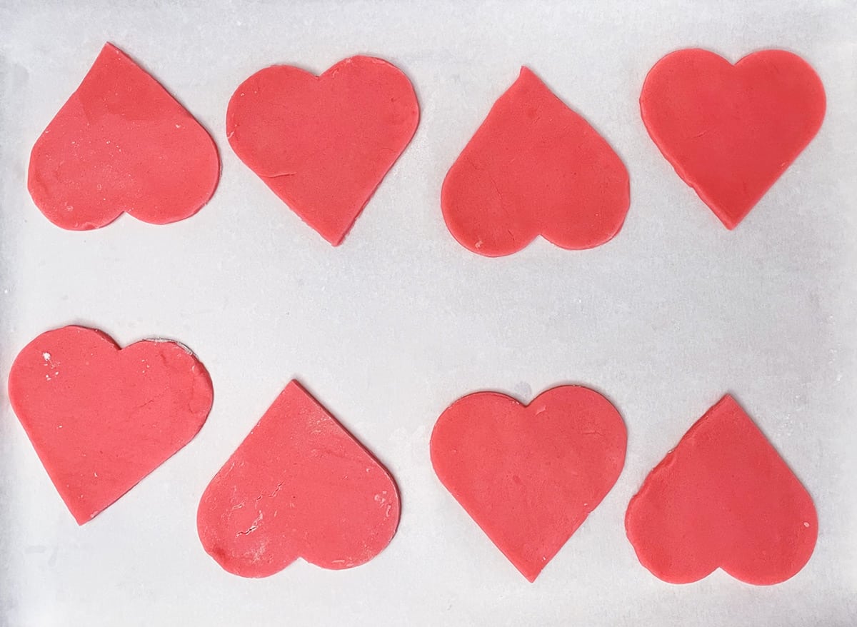 Heart sugar cookies on parchment paper ready for the oven.