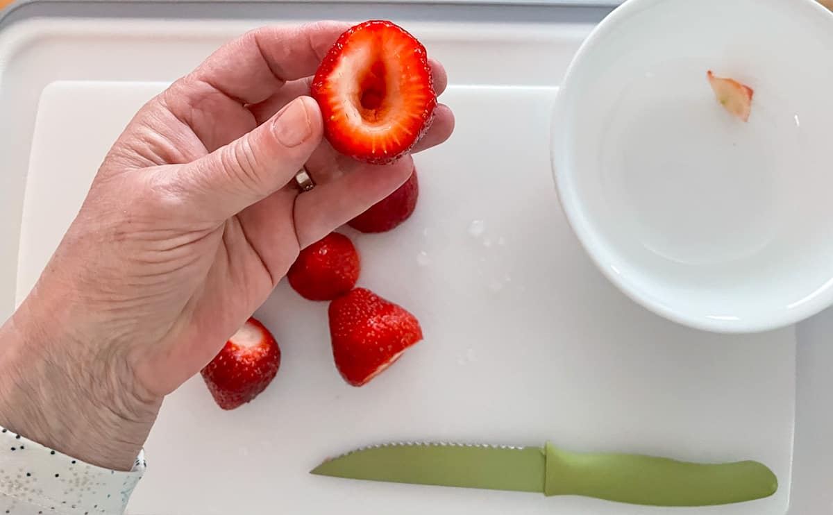 Cut the tops off of strawberries and then hull or cut out the middle.
