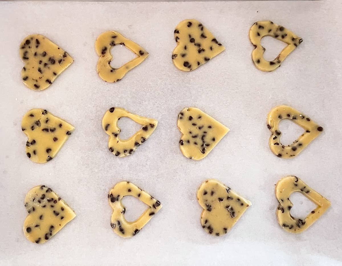 Cookies cut out with a solid heart for the bottom and a top cookie that has a small heart window for the jelly.