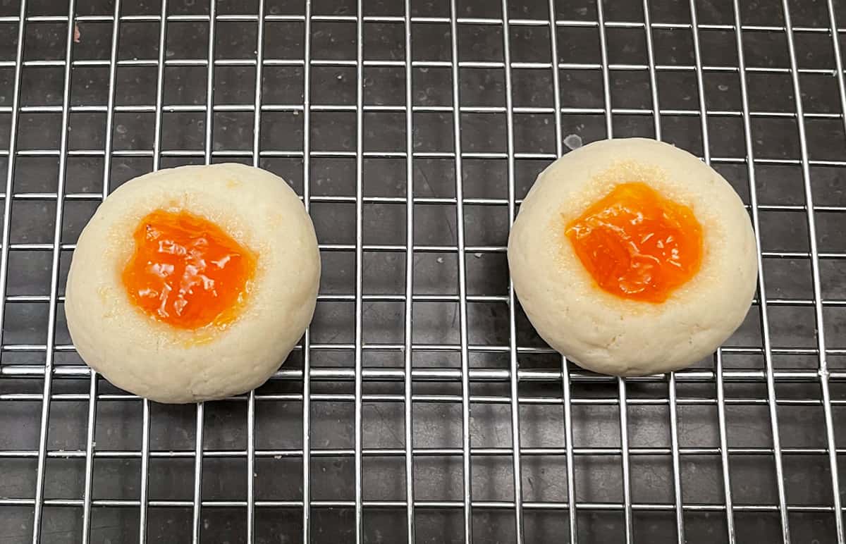 Two apricot preserves filled cookies cooling on a wire rack.