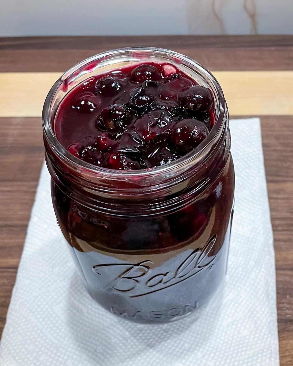 Blueberry topping for cheesecake in a glass jar.