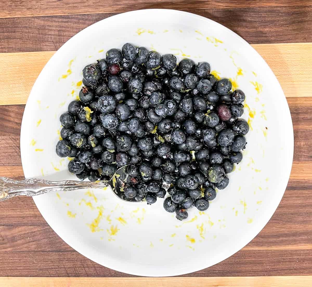 Fresh blueberries being infused with lemon zest and maple syrup.