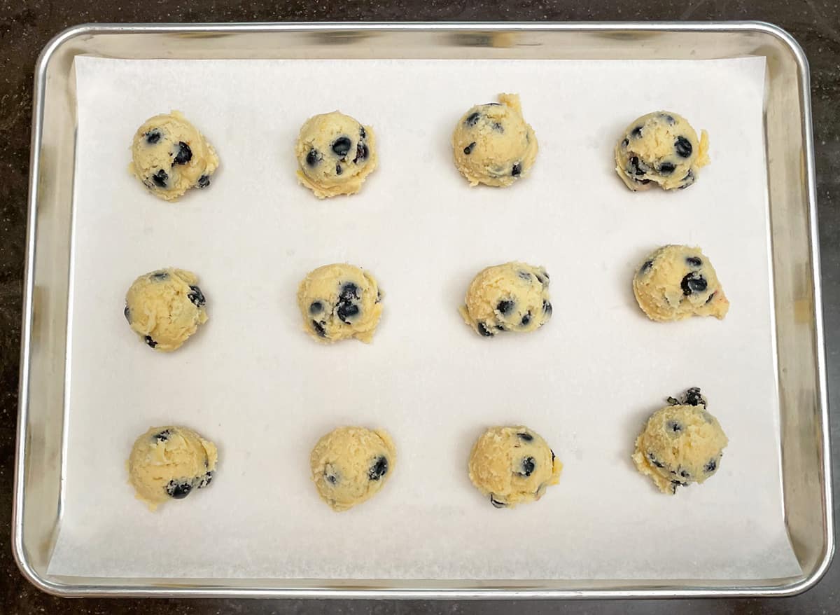 Fresh blueberry lemon maple cookies dough scooped onto sheet pan.