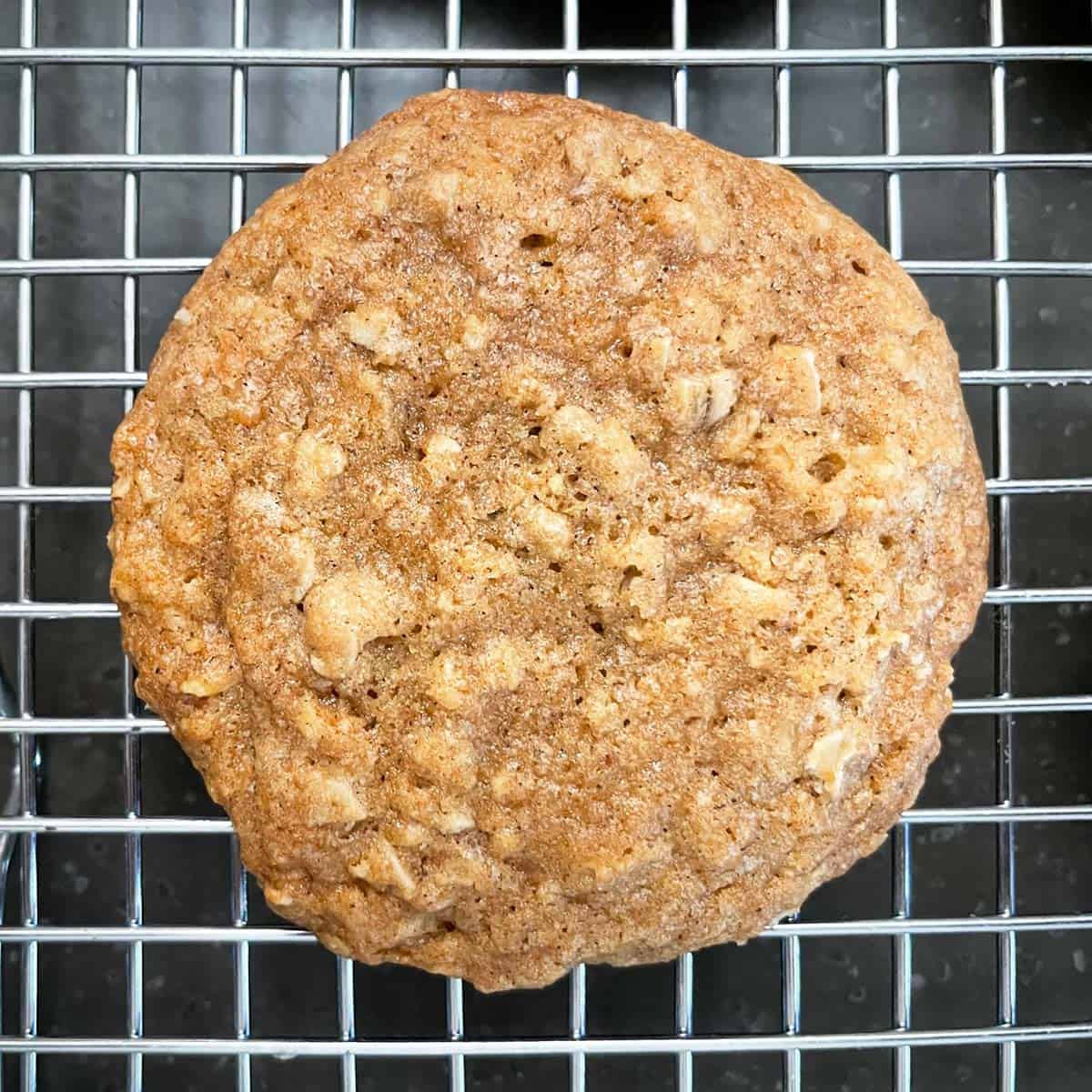 Single uniced maple oatmeal cookie sitting on a cooling rack.