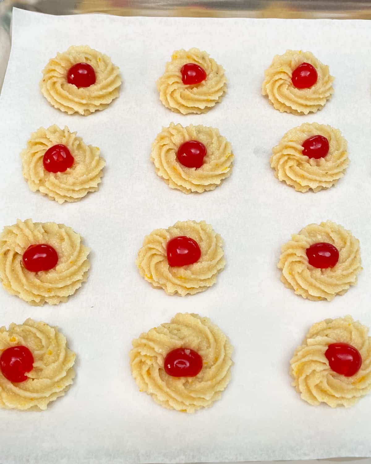 Piped two inch circles with half a cherry on top, on parchment paper.
