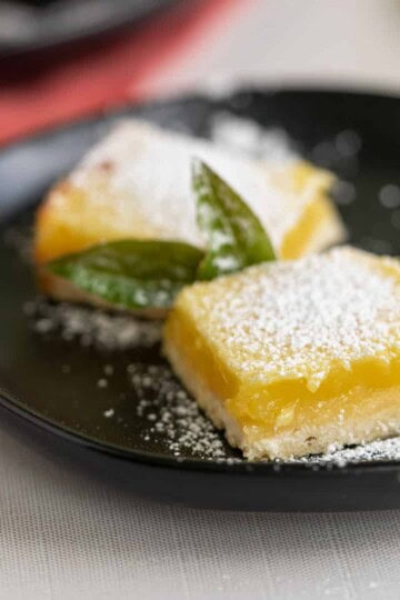 Easy lemon bars feature image on a black plate.