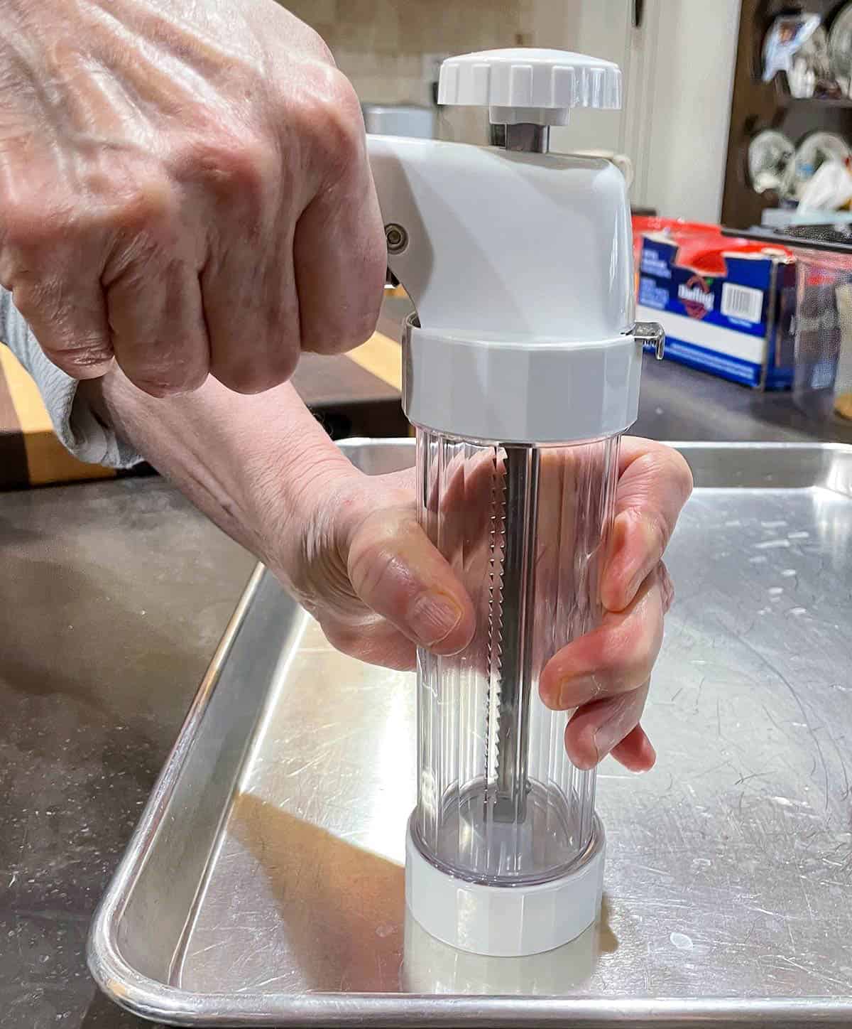 How to hold and use a cookie press on a cookie sheet pan.