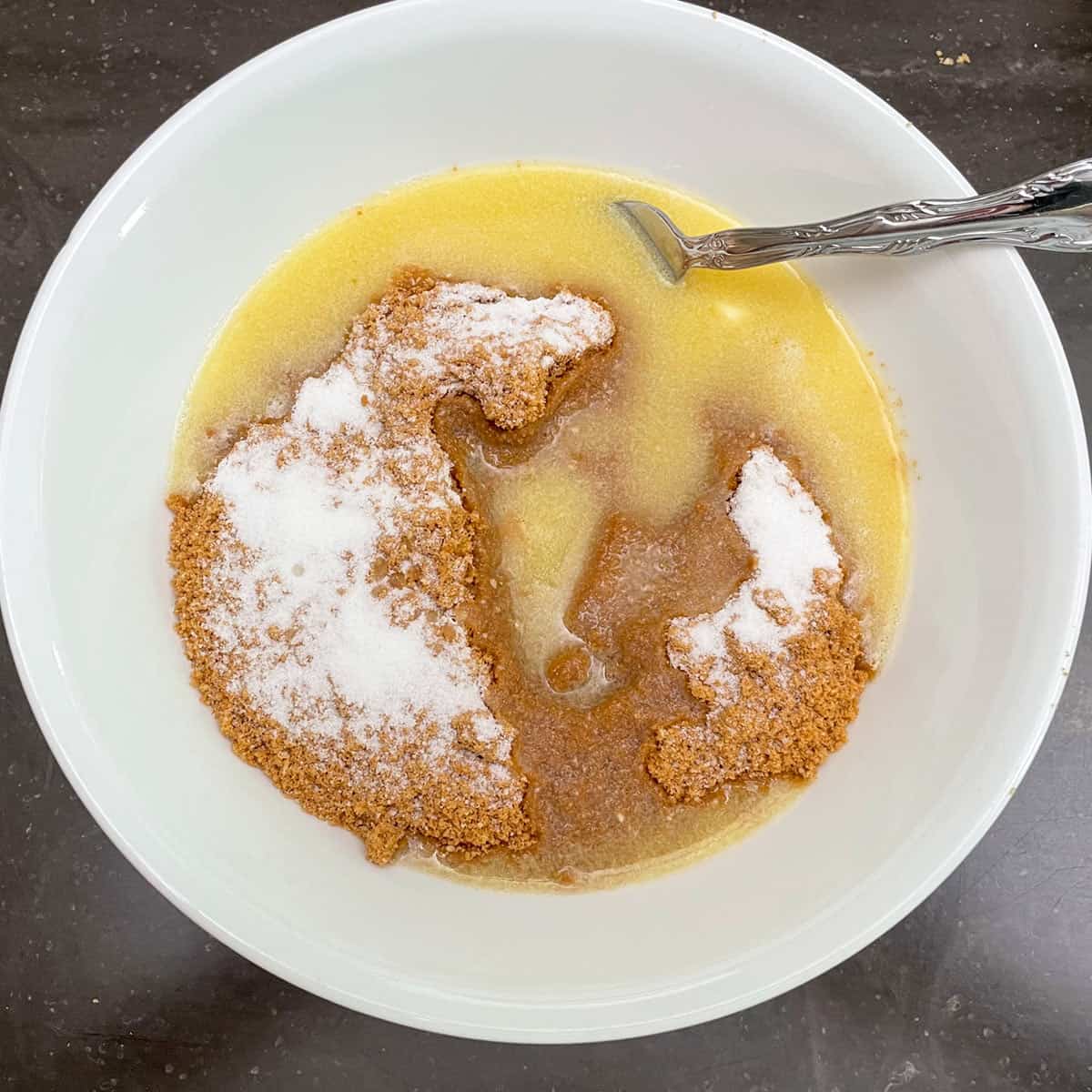 Melted butter, graham crackers, sugar in a white dish.