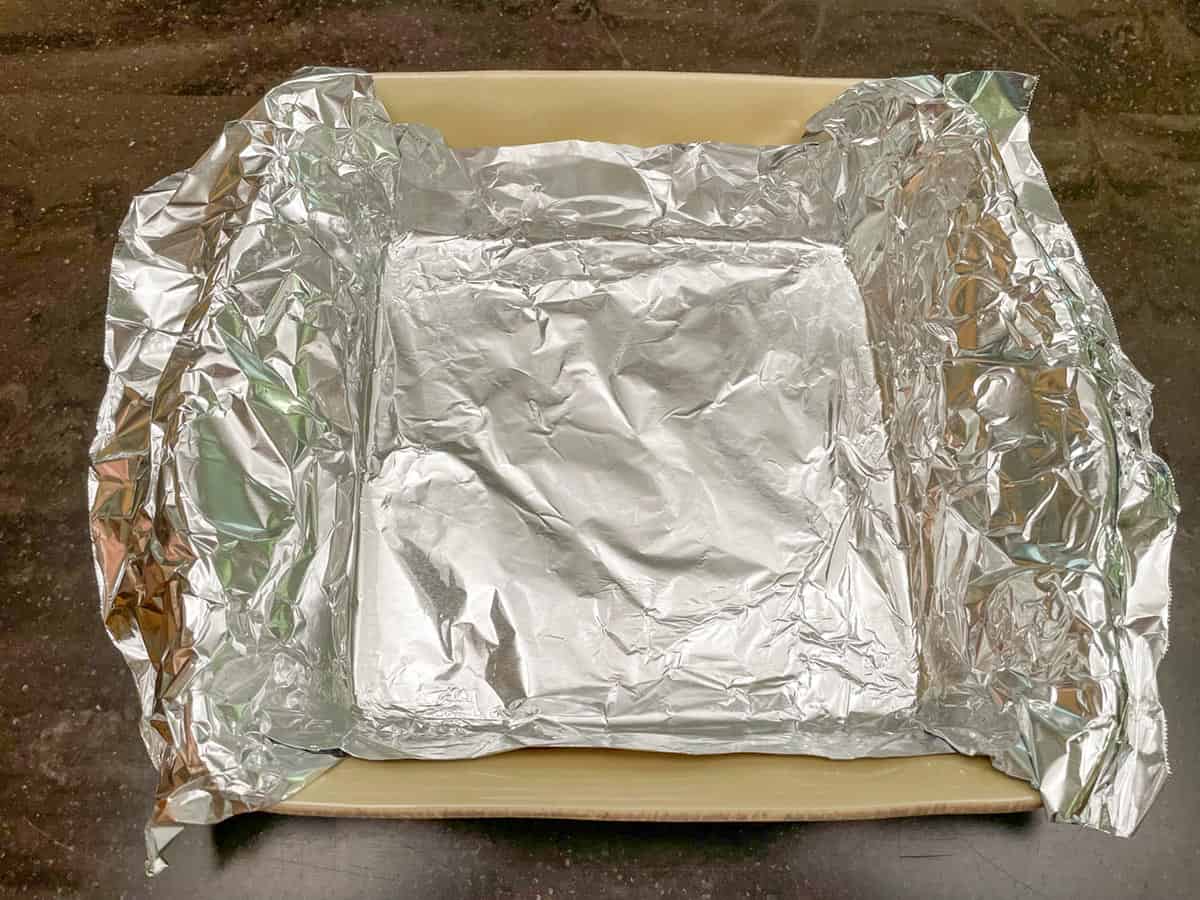Lining a baking dish with tin foil and having extended sides to pull cheesecake out of the dish.