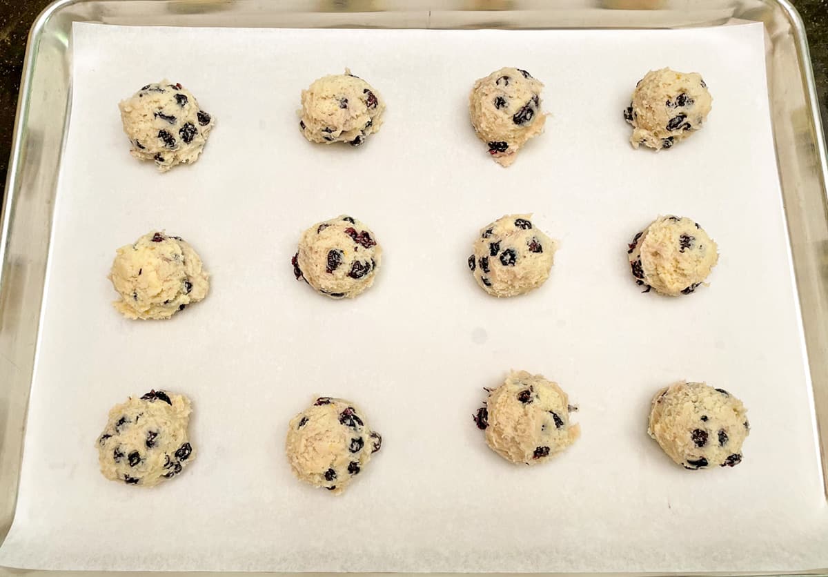 Blueberry lemon cookies scooped and on a parchment lined cookie sheet pan.