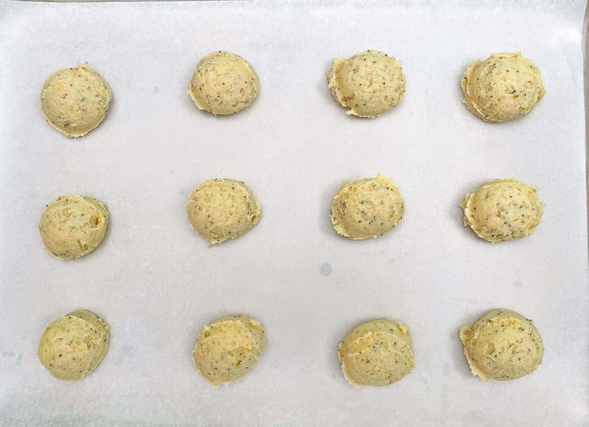 Orange ricotta cookie mounds on parchment paper ready for the oven.