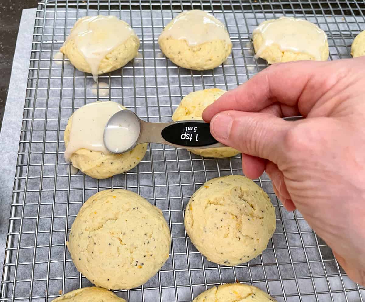 Glazing the tops of the cookies with a teaspoon.
