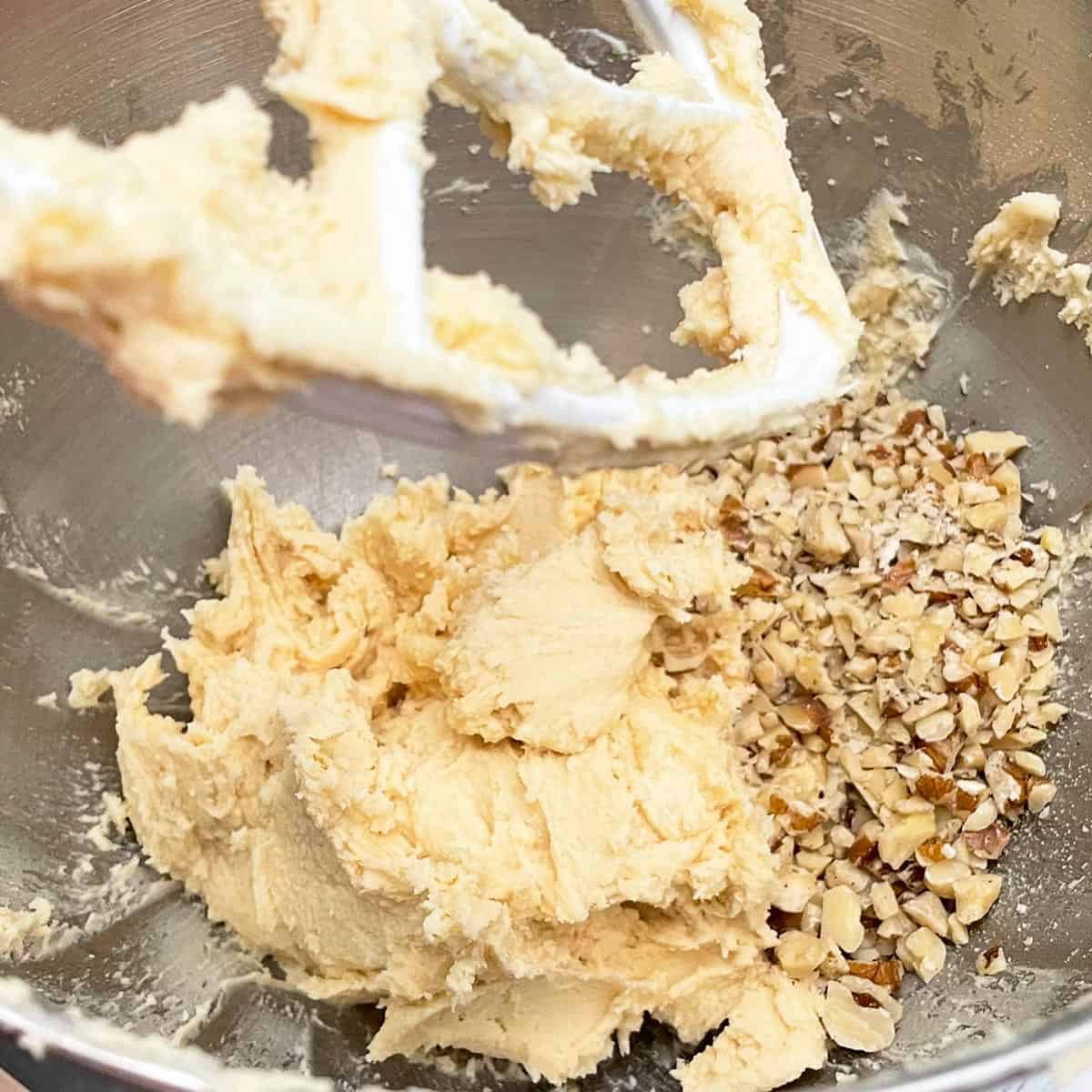 Adding black walnuts to the cookie dough in the mixer bowl.