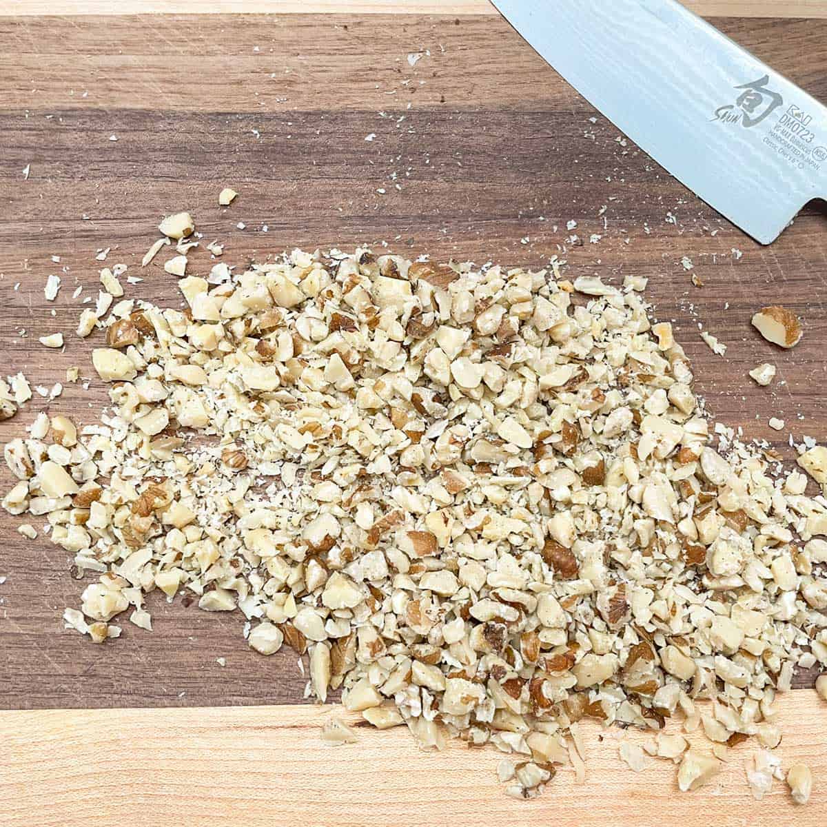 Chopped black walnuts on a cutting board with sharp knife.