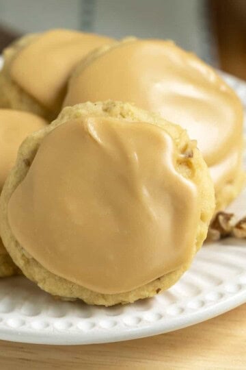 Black walnut maple cookies with brown sugar icing on a white plate for feature image.