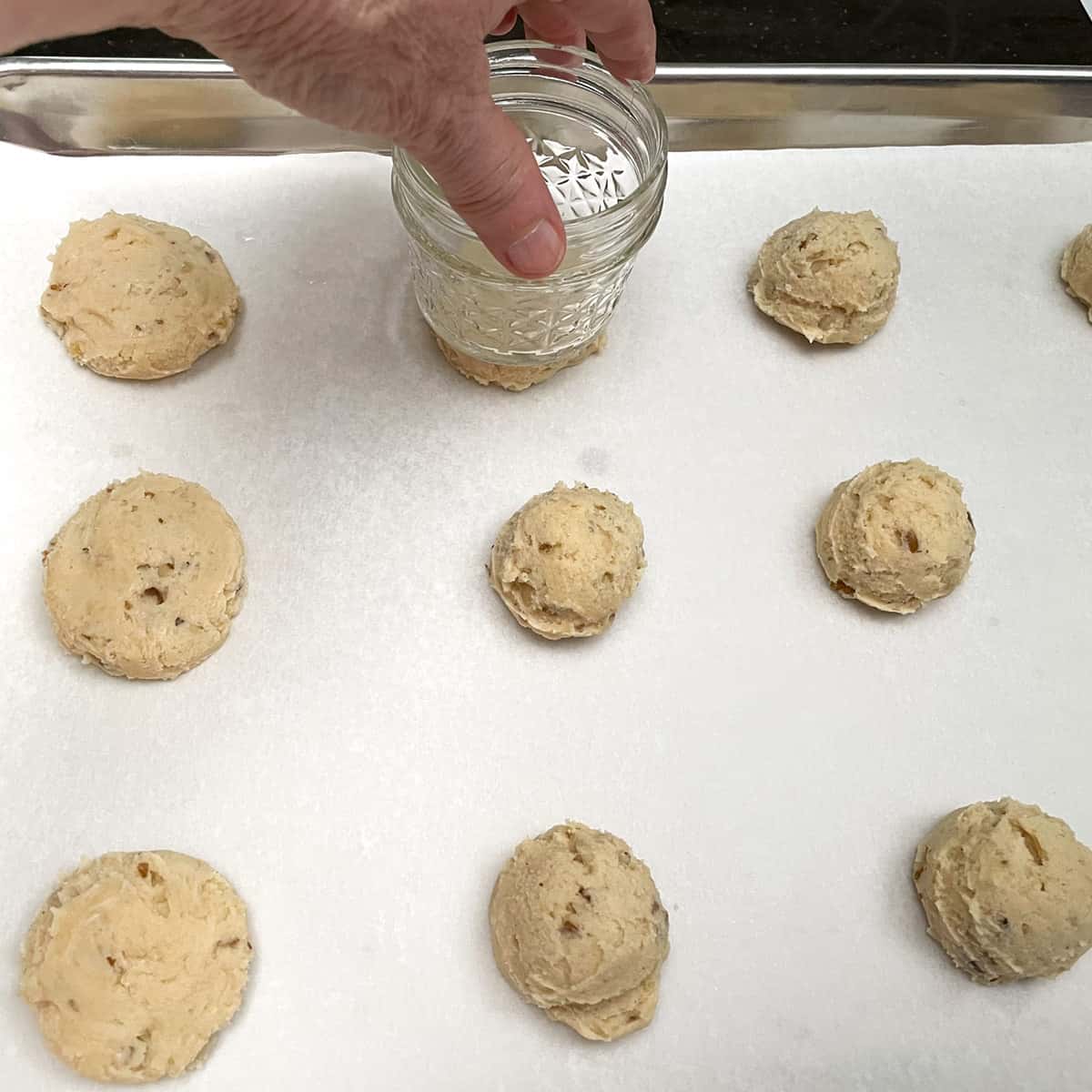 Flattening cookie dough mounds with a jar.
