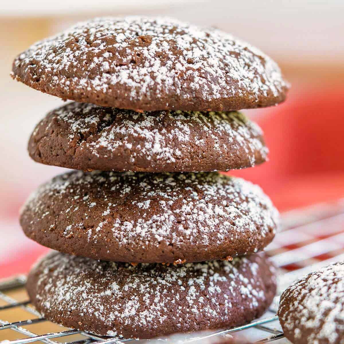 Stack of 4 chocolate cream cheese cookies with powdered sugar on top.