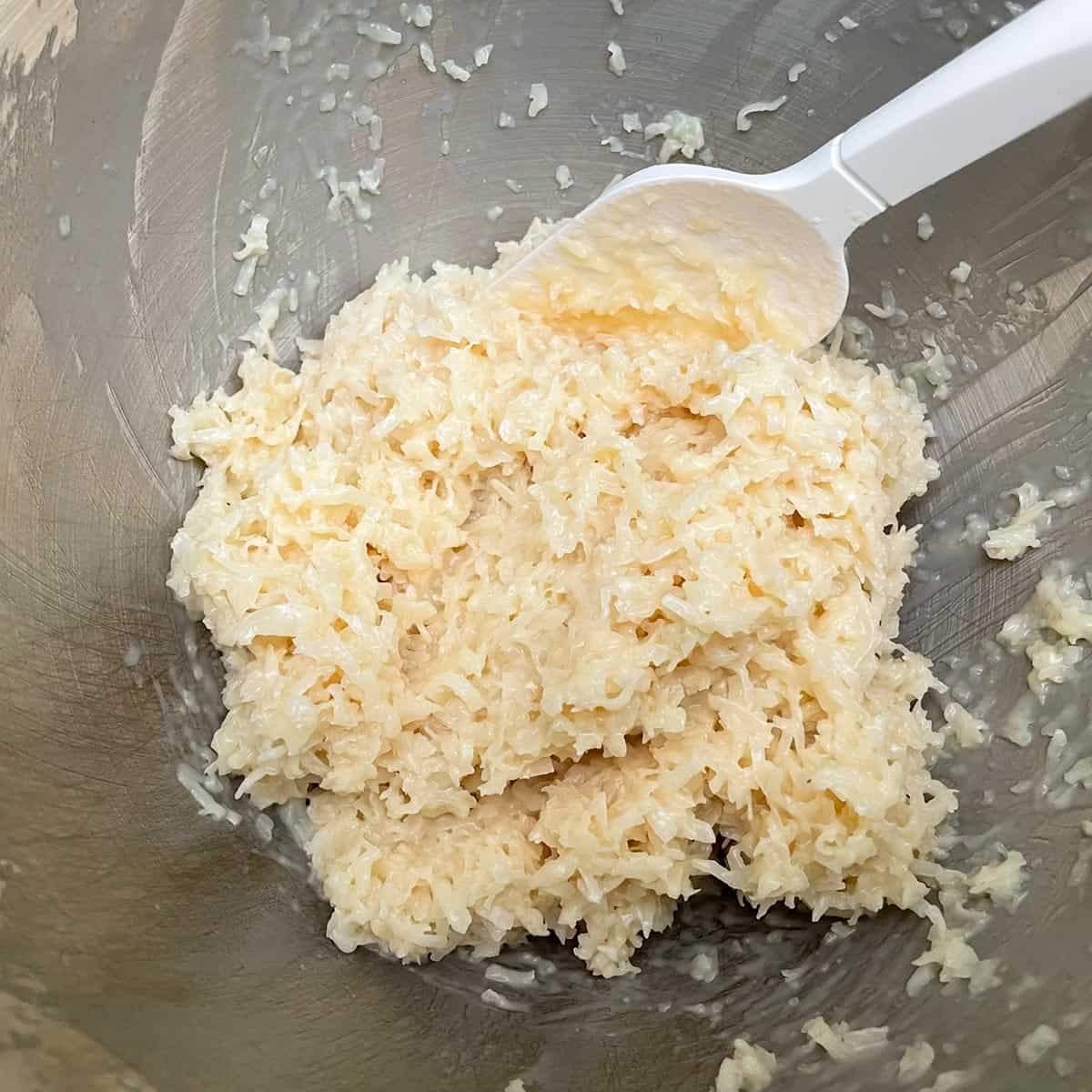 Coconut macaroon ingredients all mixed in mixer bowl.