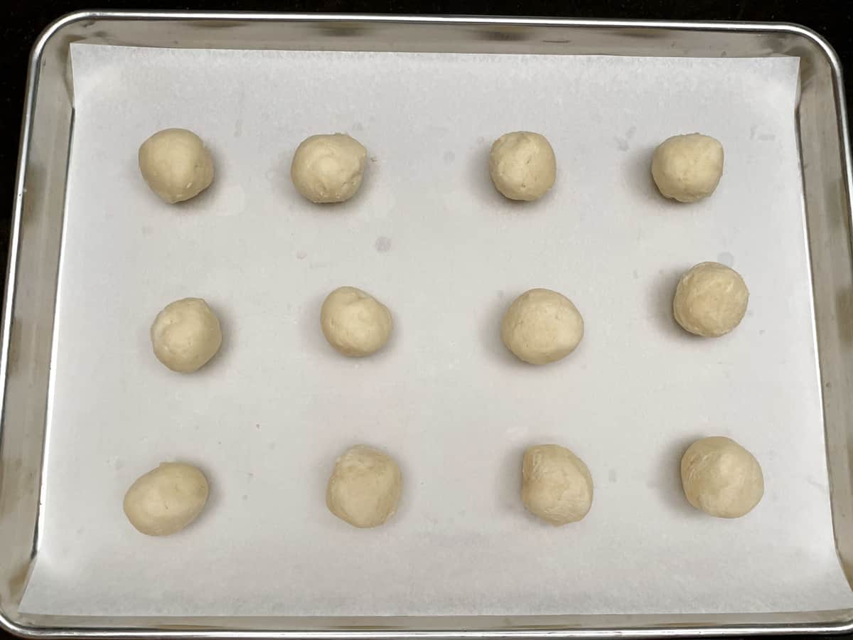 Twelve cookie dough balls before adding the thumb down through the center.
