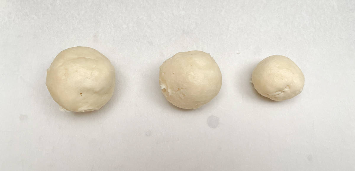 Large, medium, and small cookie dough balls made with 3 sized cookie scoopers side by side.