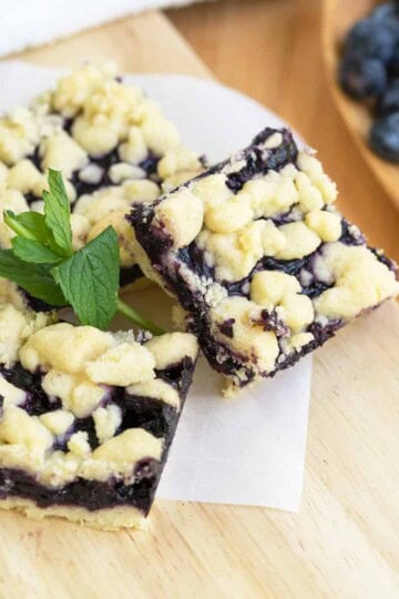 Feature picture of 3 blueberry lemon shortbread bars with a small green leaf for color.