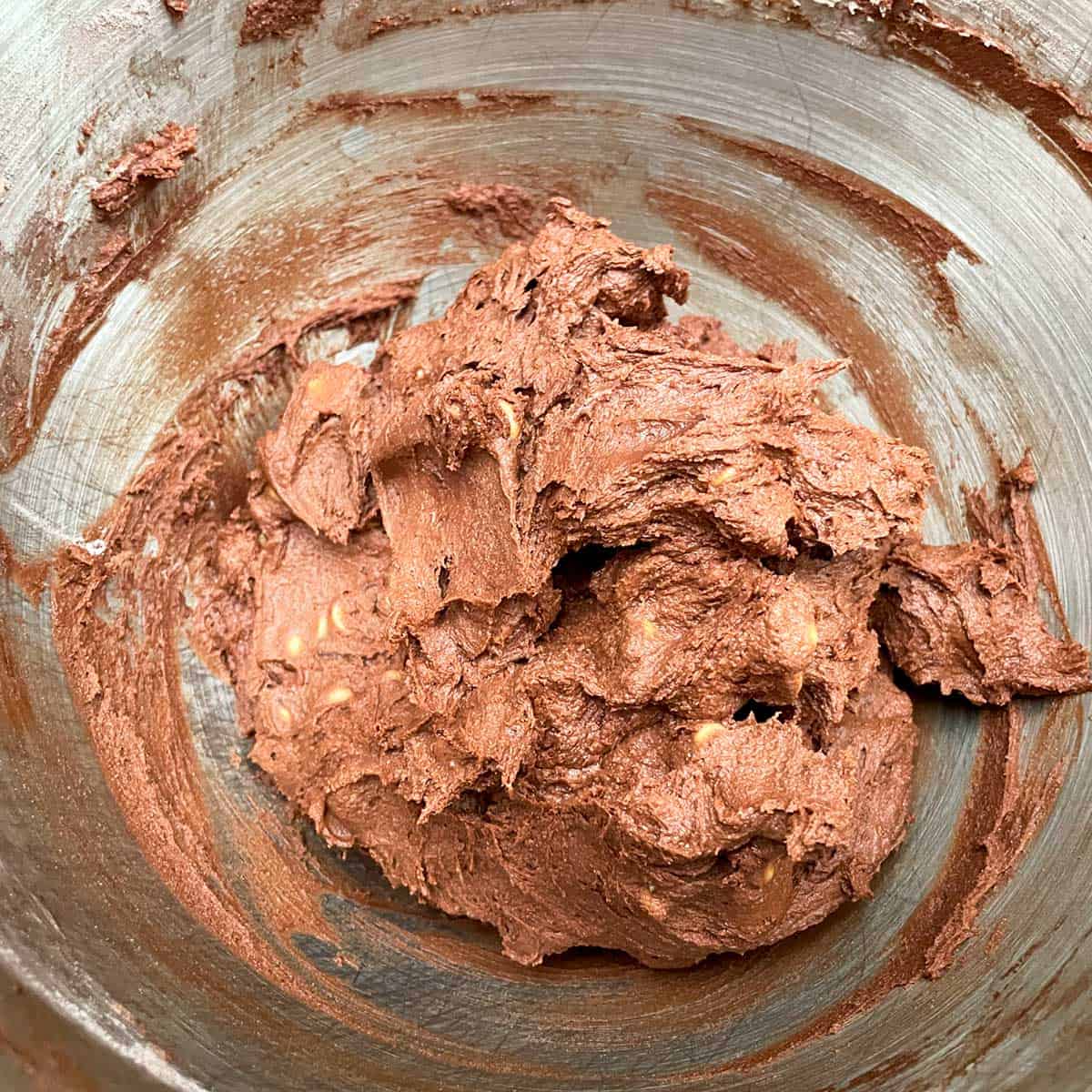 Chocolate cookie dough with peanut butter and chocolate chips mixed in a mixer bowl.