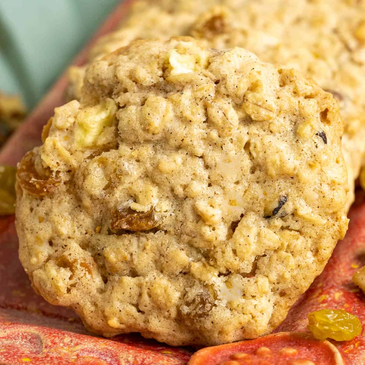 Close up of a single apple raisin walnut oatmeal cookie on a red dish.
