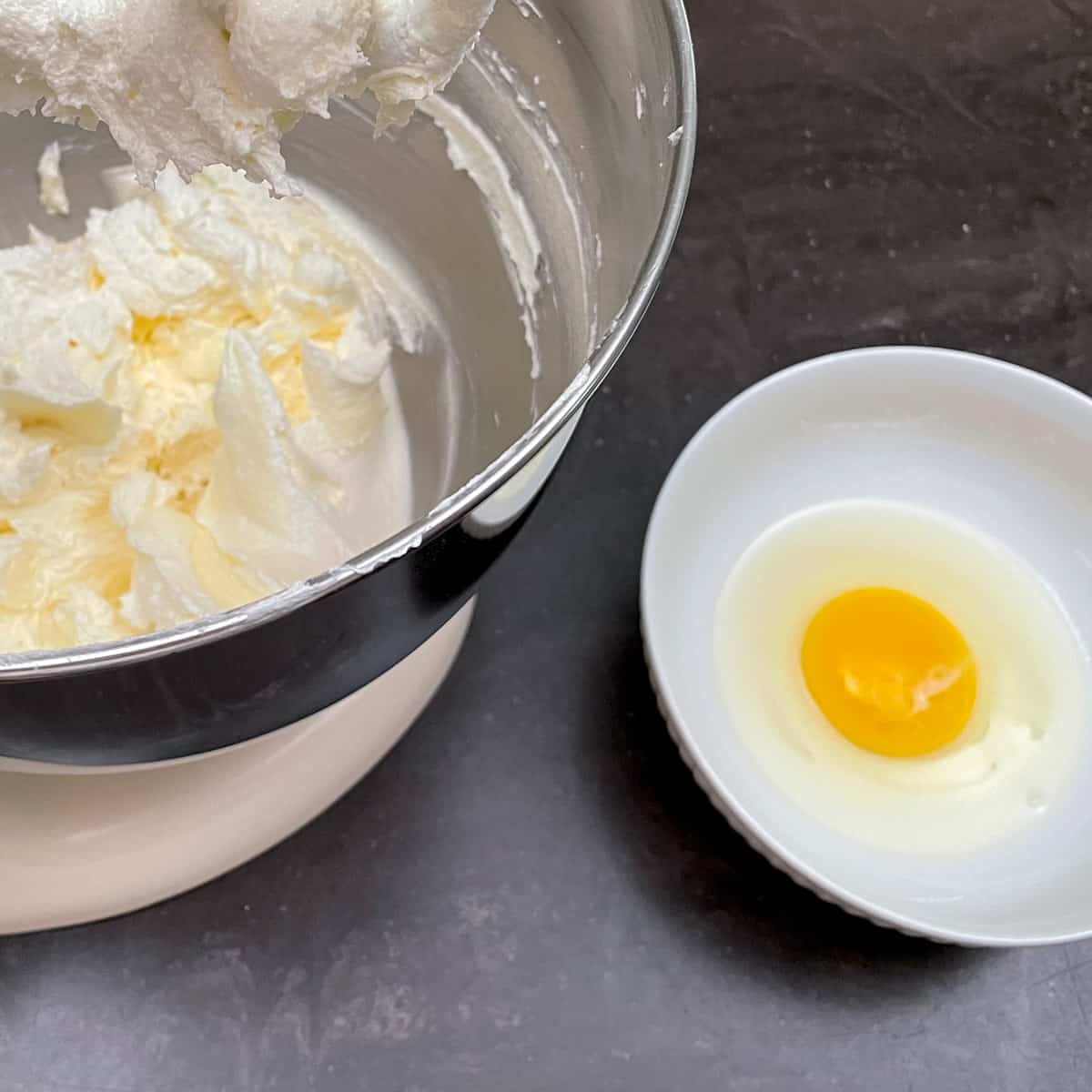 An egg in a bowl ready to be added to the cookie batter in the mixer.