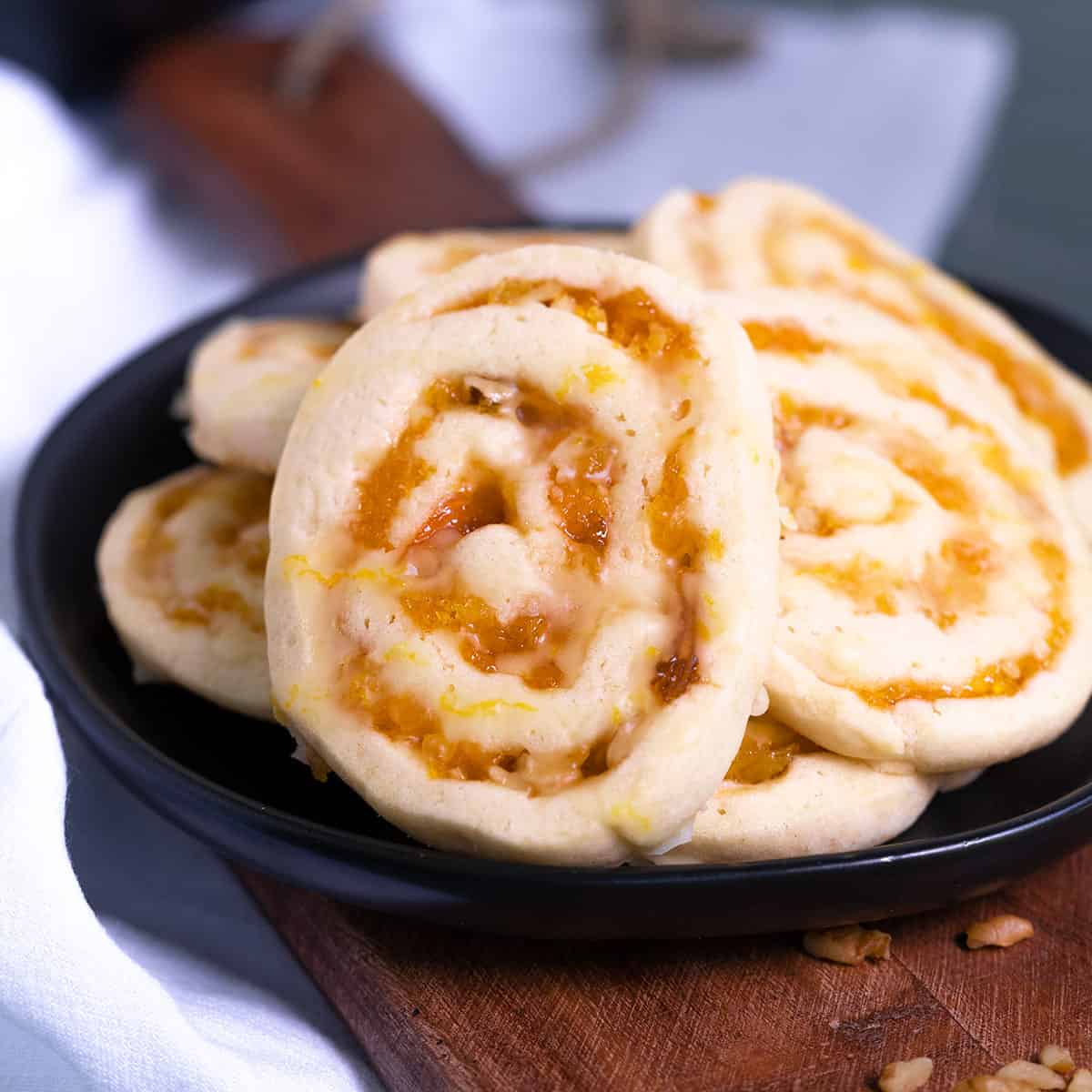 Close up of an Apricot Pinwheel cookie, sitting on a black plate.