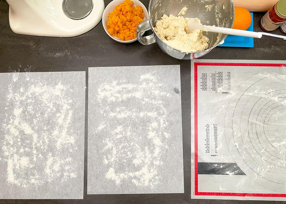 Layout of a pastry sheet and two pieces of parchment paper lightly dusted with flour.