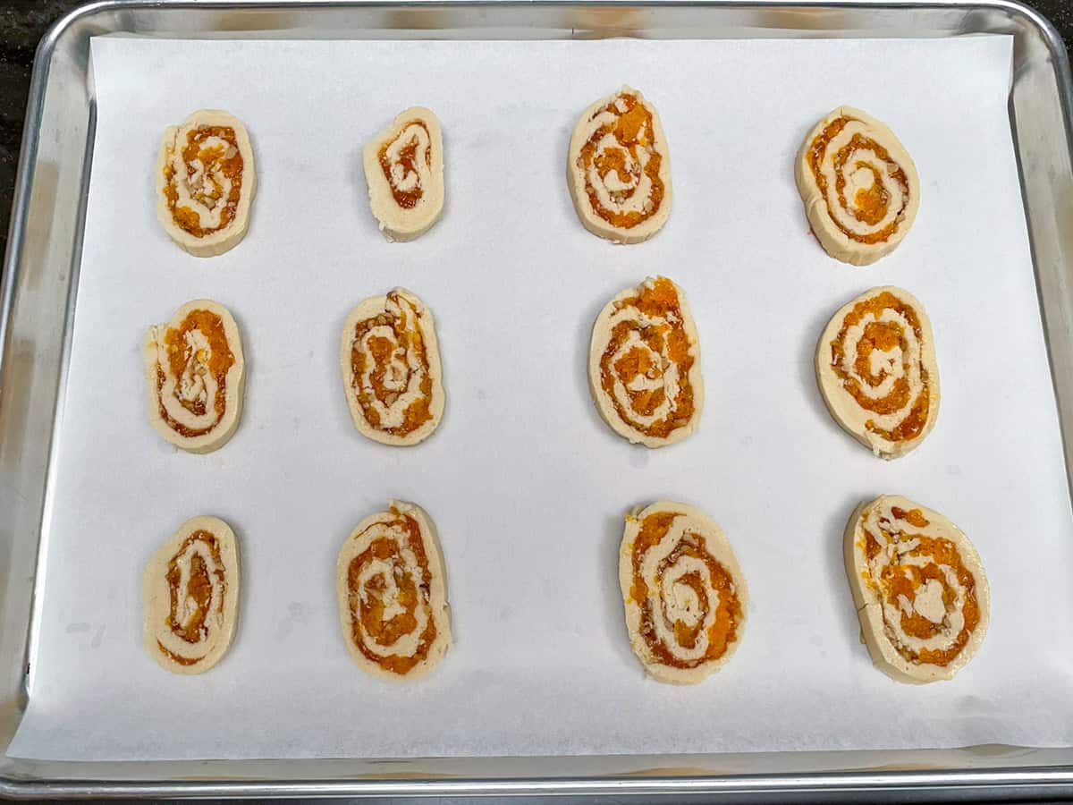 Sliced pinwheel cookies sliced and on parchment paper ready for the oven.