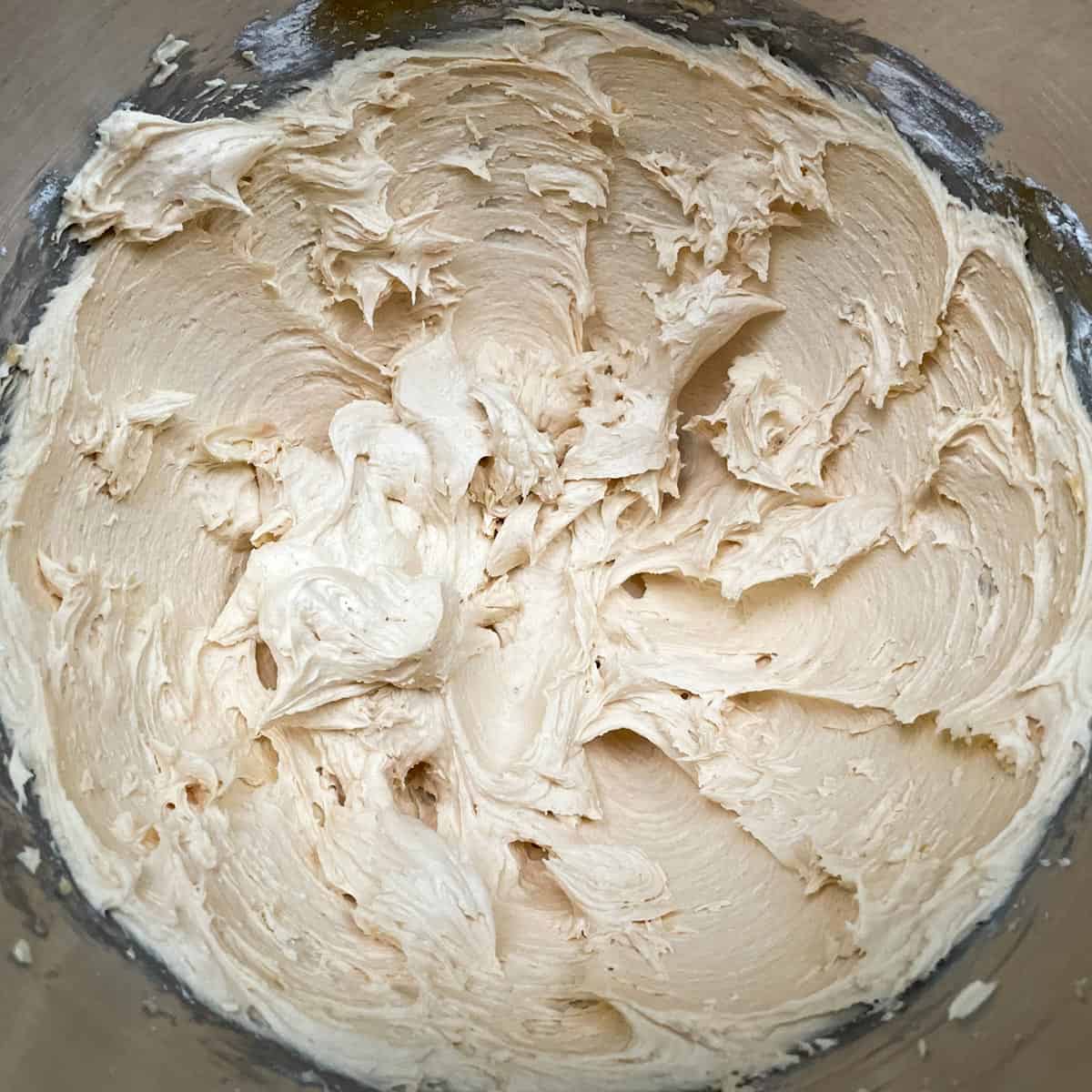 Caramel buttercream icing in a mixer bowl, looking fluffy and yummy.