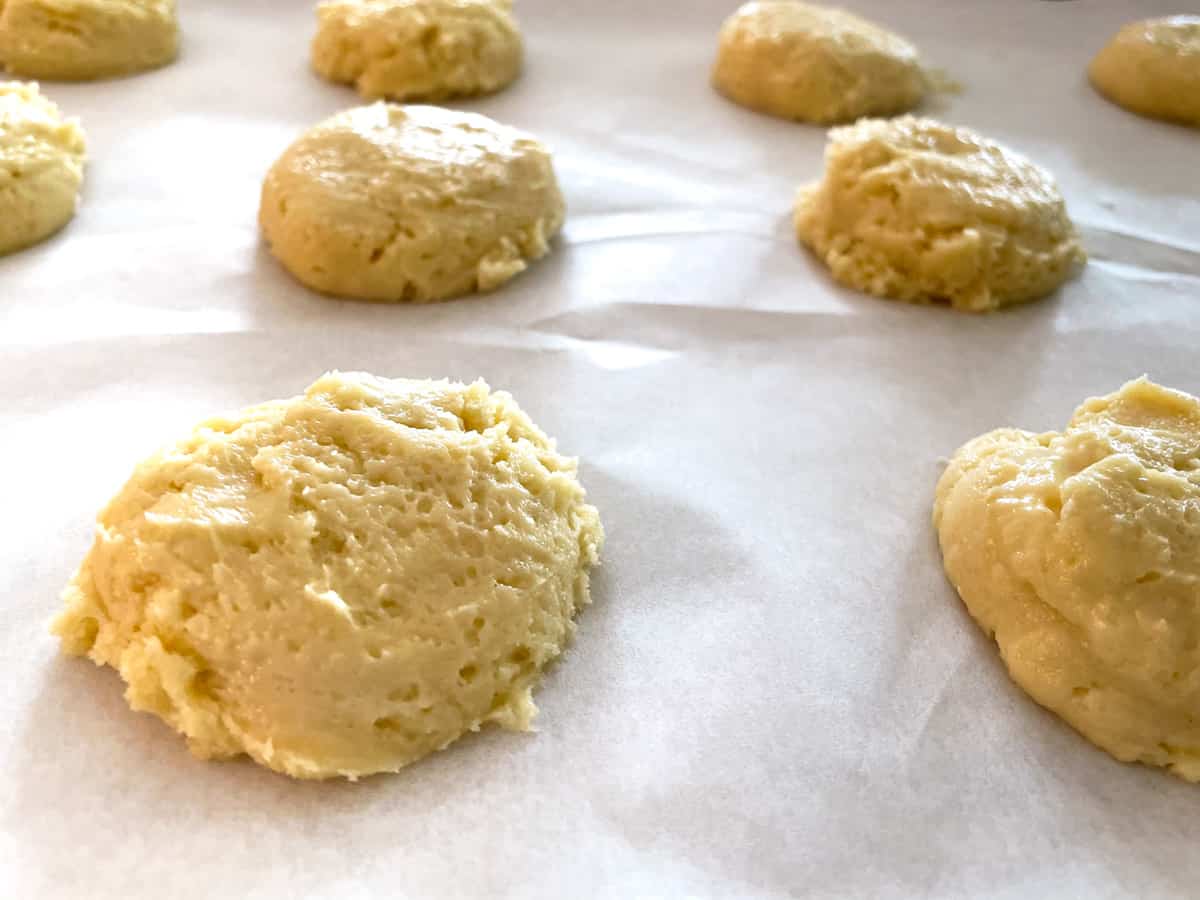 Soft cookie batter mounds on parchment paper.