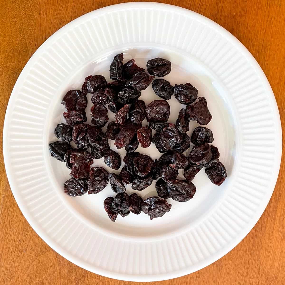 Dried cherries laying on a white plate.