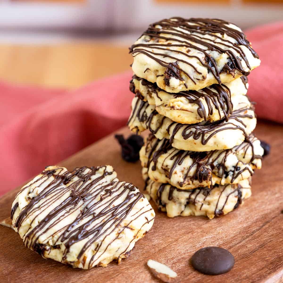 Stack of five cookies with a sixth on laying flat on the wood board.