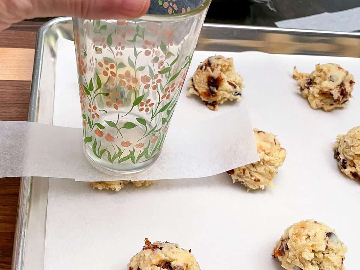 Strip of parchment paper between cookie mound and the glass for flattening mound.