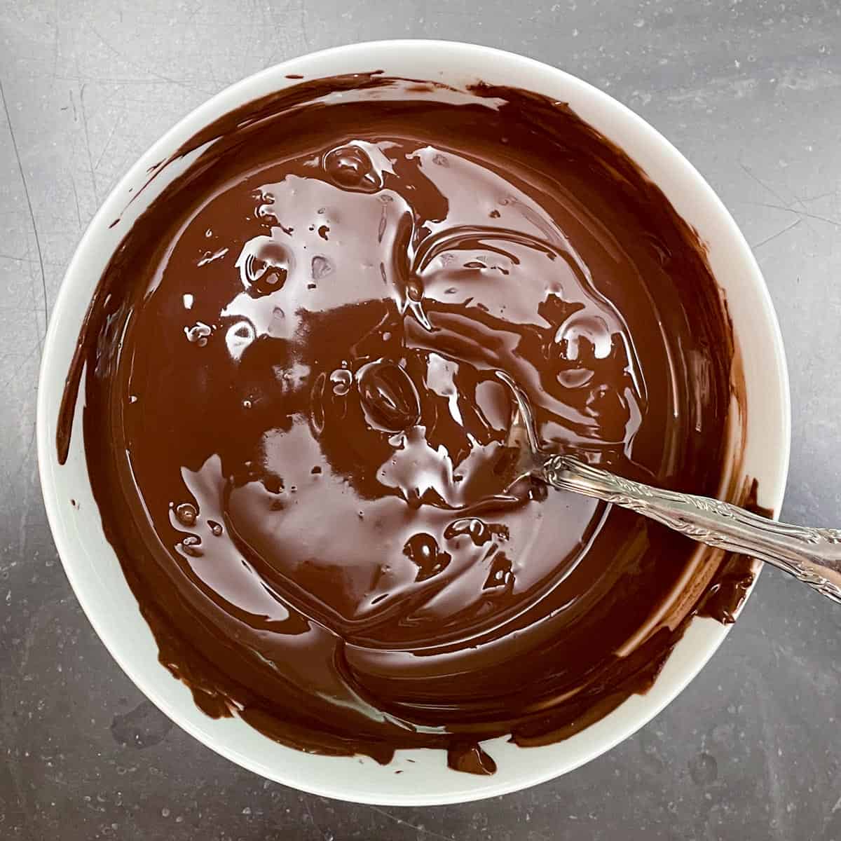 Melted dark chocolate in a white bowl.