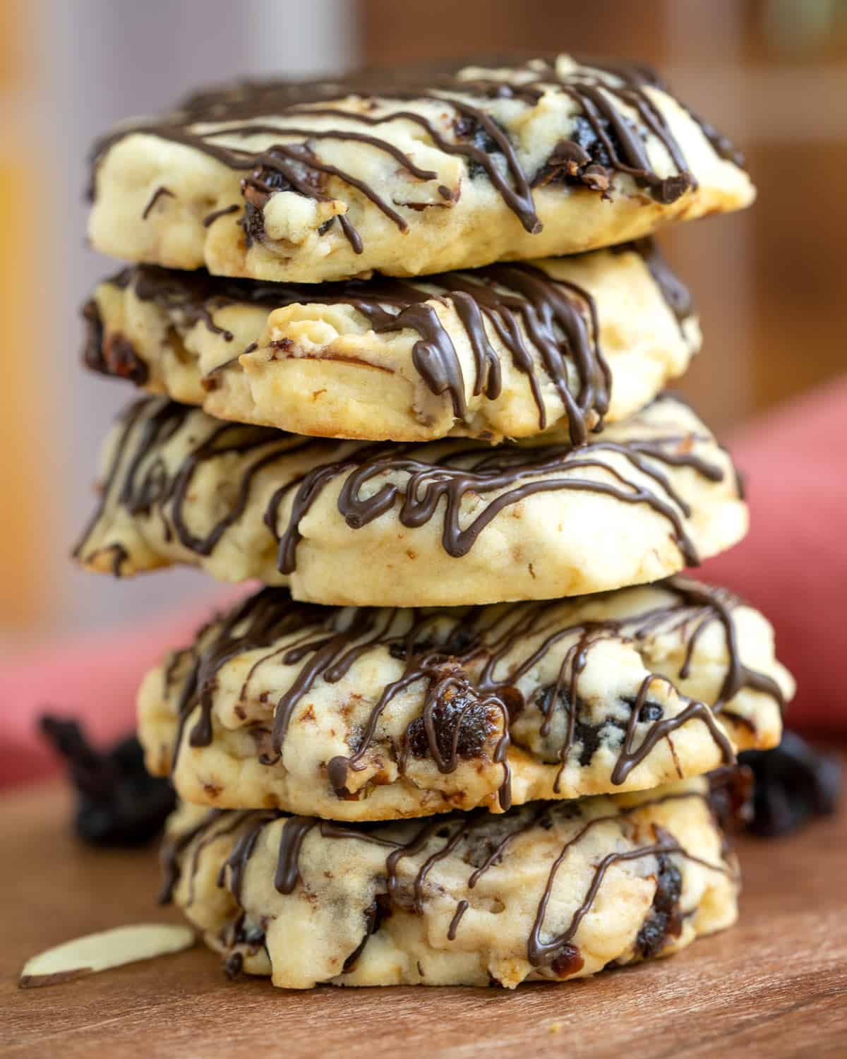 A stack of cherry almond cookies with a dark chocolate drizzle.