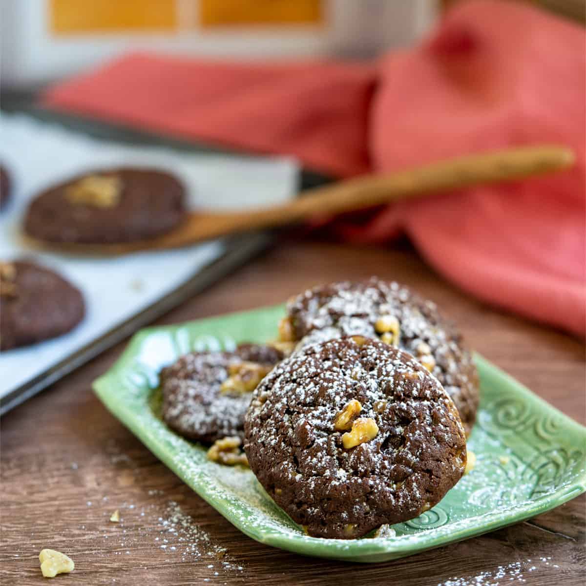 Chocolate Cookies with Orange and Toffee Bits sitting on a green plate with more cookies in the background.