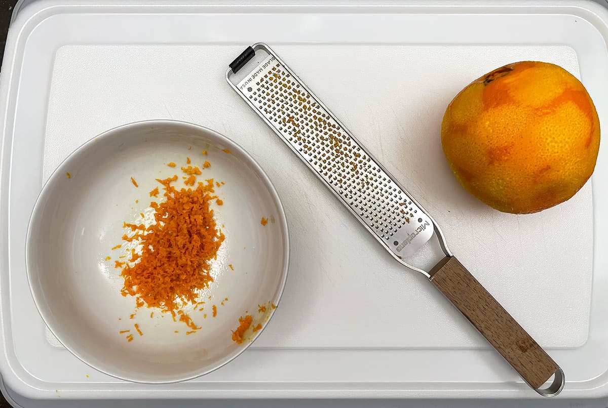 Zesting an orange on a cutting board.