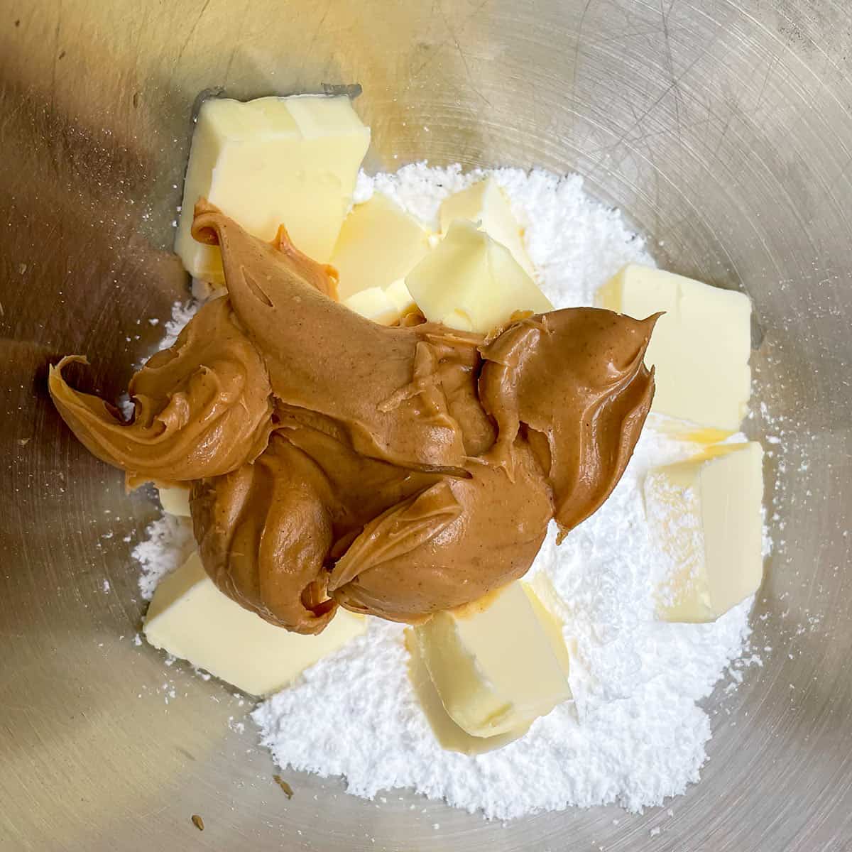 Three ingredients for peanut butter frosting in a mixer bowl.