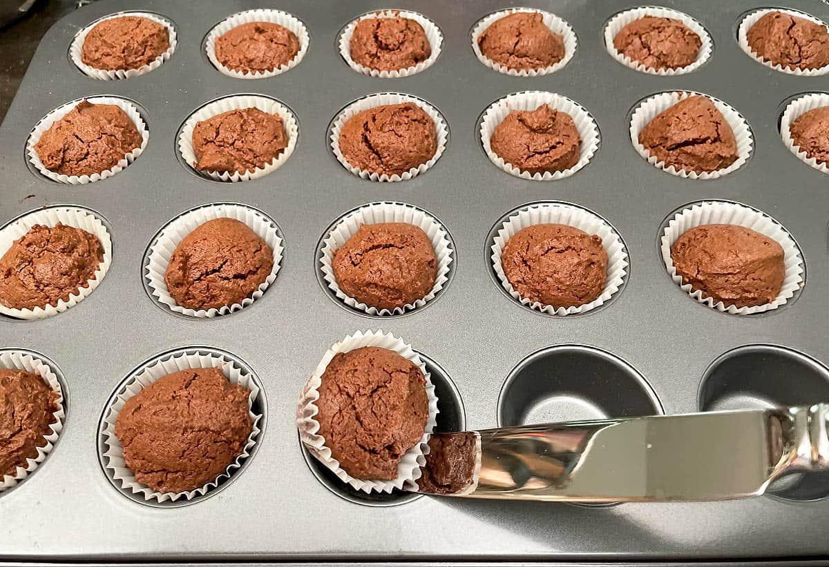 Lifting a baked chocolate cupcake cookie out of the mini cupcake pan.