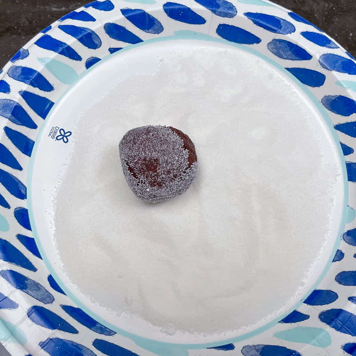 Cookie dough ball getting rolled in sugar.