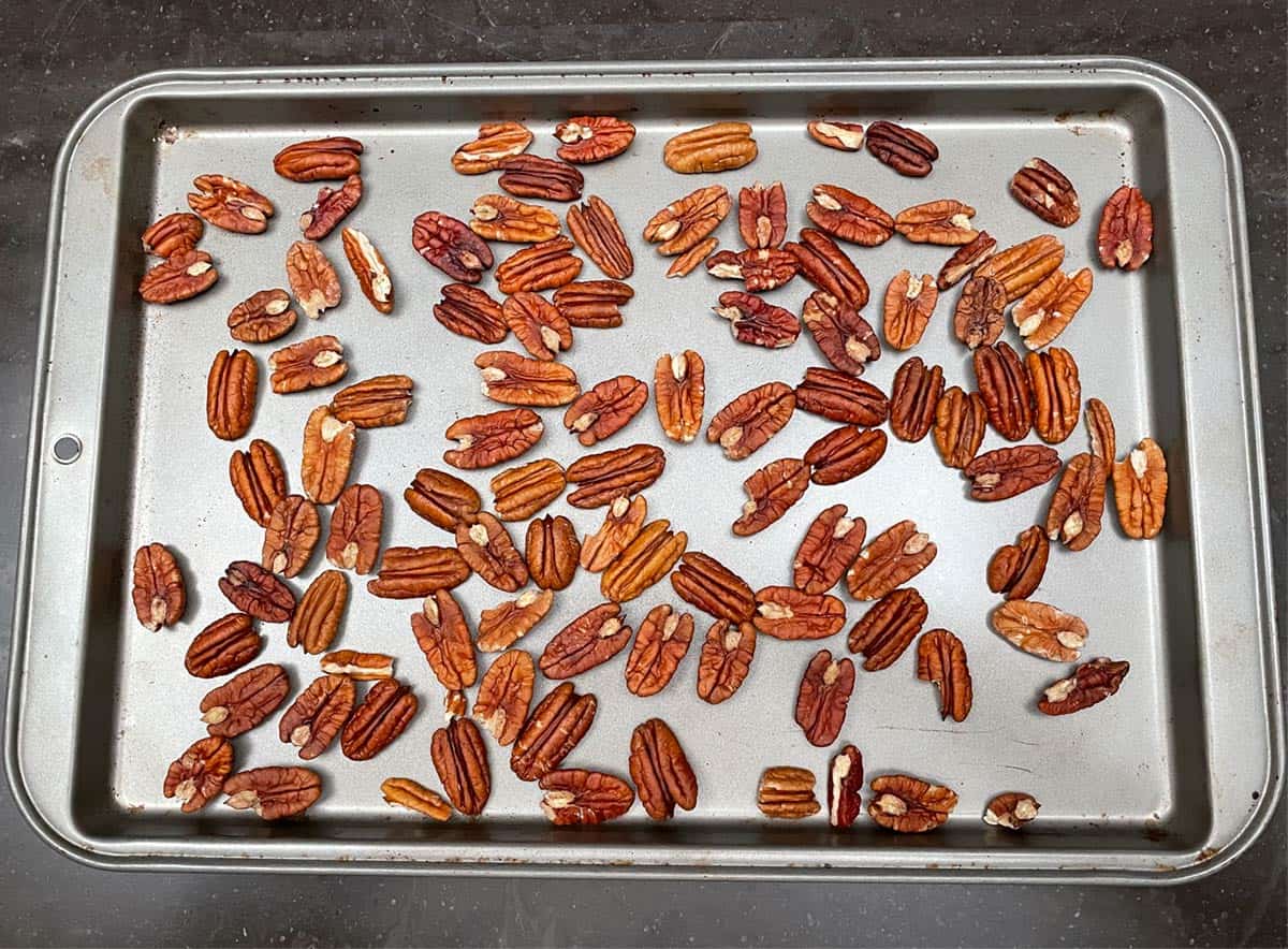 Pecan halves on a sheet pan ready to be roasted in the oven.